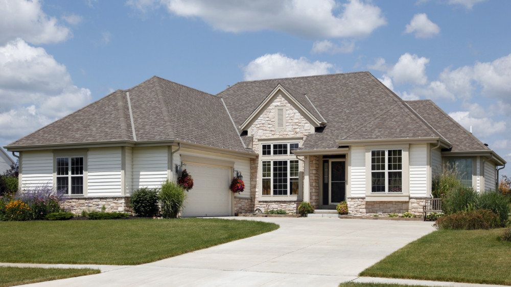 A home exterior painted in white with beige trim and a partial rock front.