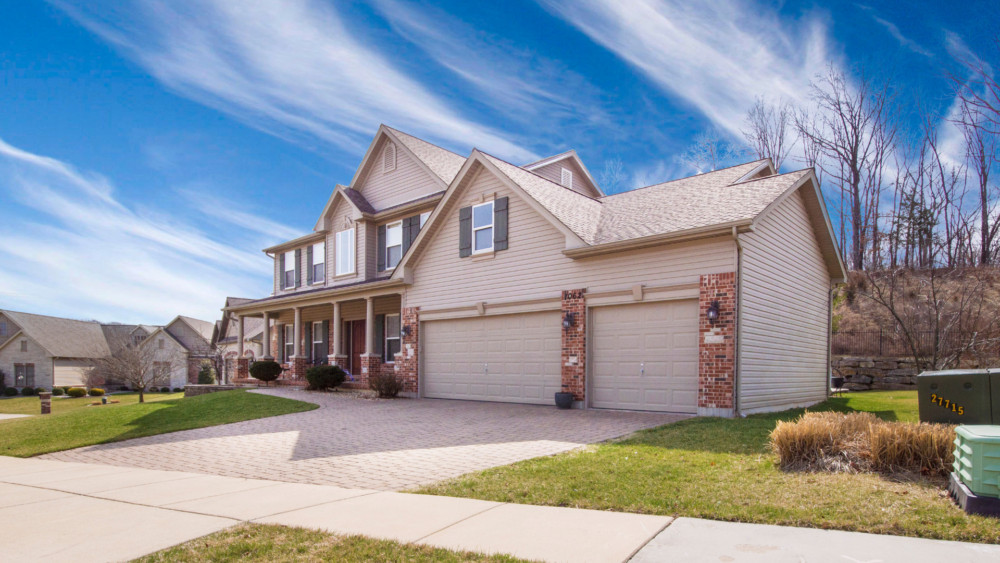 A home exterior painted in beige with a partial brick front.